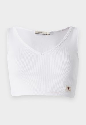 Witte geribbelde bralette met een V-halslijn, brede schouderbanden en een klein logo-label aan de onderrand. Gemaakt van een zachte, rekbare stof.