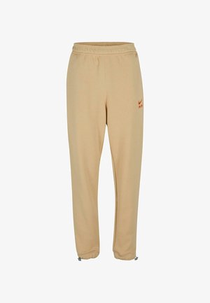 Bežové Nike teplákové nohavice s elastickým pásom, oranžovým logom, zúženými nohavicami a nastaviteľnými manžetami na členkoch. Vyrobené z mäkkej tkaniny.