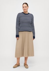 Navy and white striped knitted sweater, pleated beige midi skirt, and beige flats with a strap across the foot. Textured fabrics, relaxed fit.