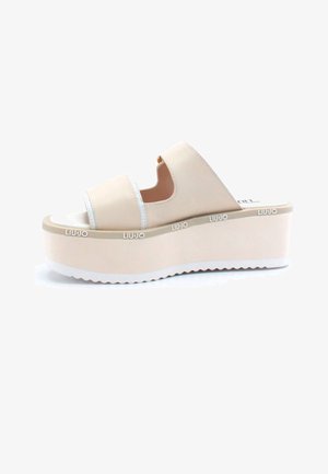 Sandales à plateforme beiges avec deux larges brides, design ouvert à l'avant, et semelle texturée blanche. Marque visible sur le côté.