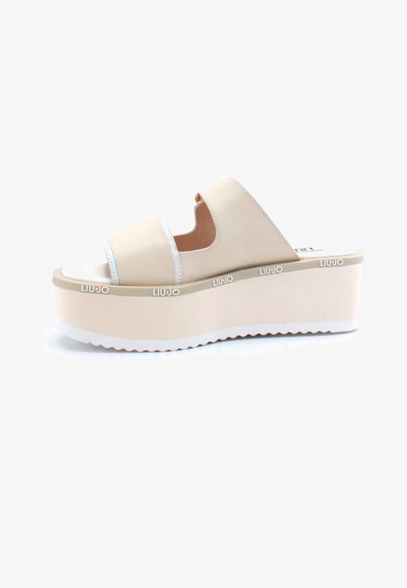 Sandales à plateforme beiges avec deux larges brides, design ouvert à l'avant, et semelle texturée blanche. Marque visible sur le côté.