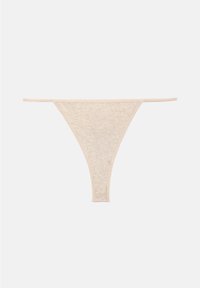 String en coton beige avec fines lanières latérales et un design simple et sans couture sur un fond clair uni.