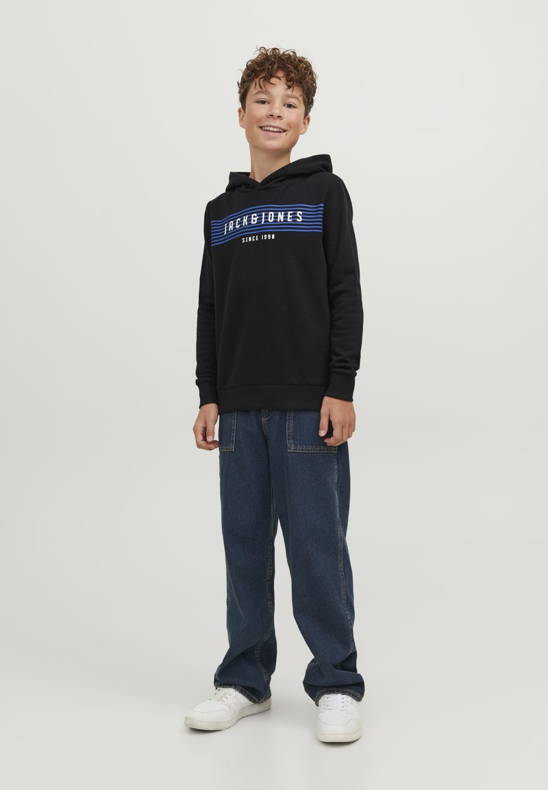Sudadera negra con gráfico de rayas azules y diseño de texto, combinada con pantalones vaqueros de mezclilla azul holgados y zapatillas blancas. Tejido suave y corte relajado.