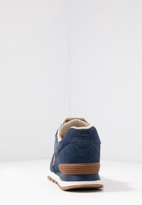 New Balance-sneaker i marinblå mocka med en texturerad stickad överdel, bruna accenter på hälpartiet och en gummisula.