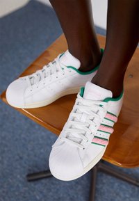 Vita lädersneakers med gröna och rosa detaljer, featuring en texturerad tåkupp, tre randig design och vadderad hälkrage.