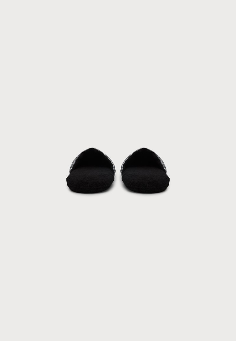 Pair of black fuzzy slippers with open backs and gray textured straps, shown from a frontal view on a plain background.
