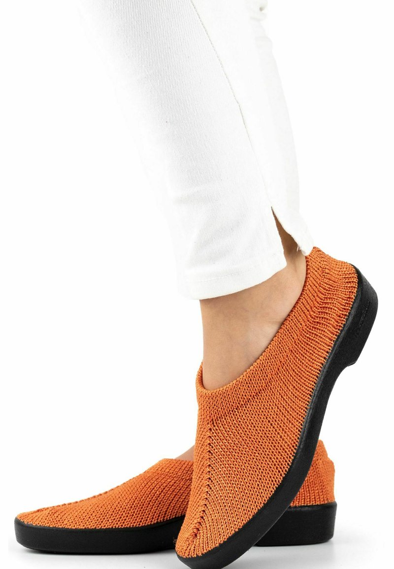 Scarpe slip-on con una tomaia in maglia testurizzata arancione e una suola in gomma nera, caratterizzate da un design senza cuciture e un'apertura ampia per una facile vestibilità.