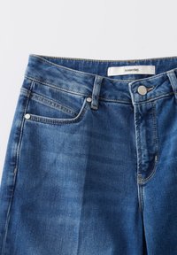 Blauwe denim spijkerbroek met een rechte snit, voorzien van een knoop aan de voorkant, vijf zakken en een label met de tekst "someday." Verweerde textuur op de stof.