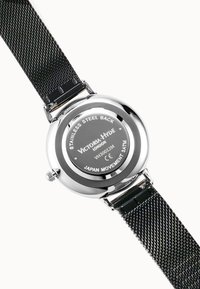 Orologio con cassa in acciaio inossidabile e cinturino in rete nera; cassa rotonda; dettagli del marchio e del movimento incisi; design minimalista.