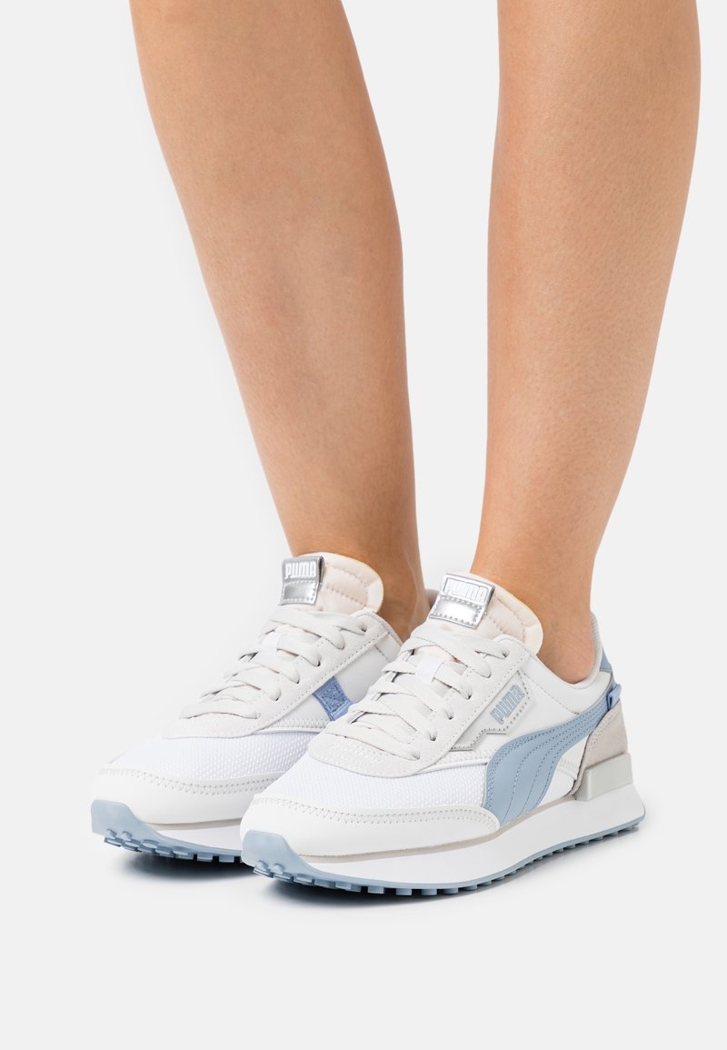 Baskets blanches et bleu clair en mesh et cuir, avec lacets plats, col rembourré et semelle extérieure en caoutchouc. Logo Puma sur la languette.