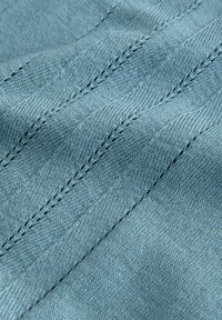Plavi pleteni materijal s glatkom teksturom i uzorkom dijagonalnih linija. Sadrži suptilne detalje šivanja.