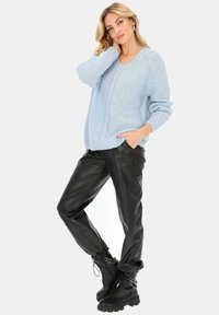 Jasnoniebieski sweter z dzianiny z dekoltem w kształcie litery V, długimi rękawami i fakturowanym wykończeniem. W połączeniu z czarnymi spodniami z sztucznej skóry i czarnymi sznurowanymi botkami.
