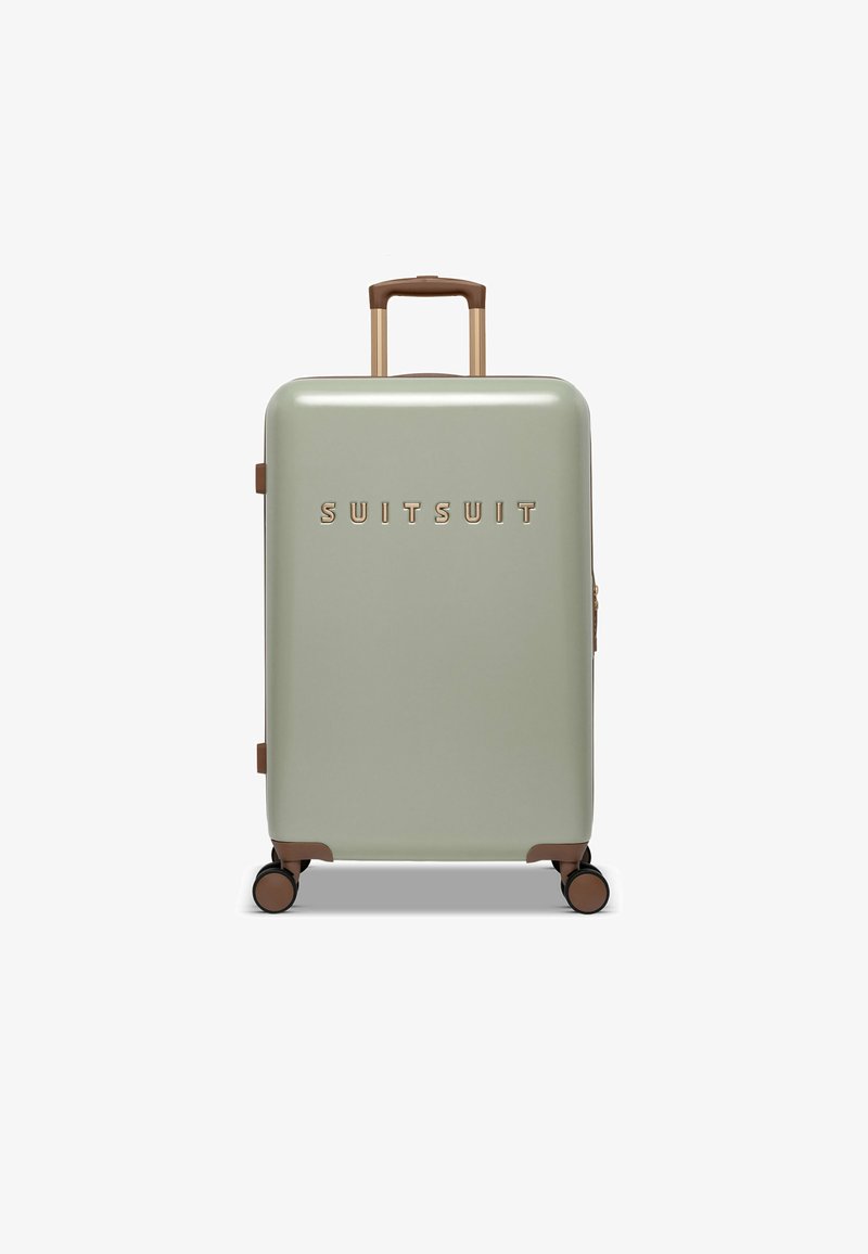 Hartschalentrolley in gedämpftem Grün, mit glänzender Oberfläche, bronzefarbenen Akzenten und einem teleskopierbaren Griff. Vier Räder für Mobilität.