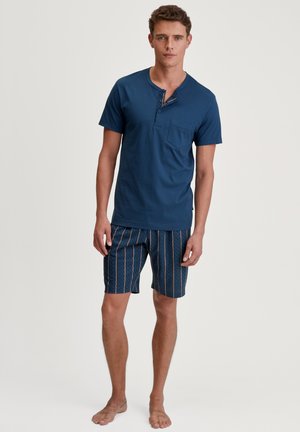 Marineblauw korte mouwen henley shirt met een knoopsluiting, gecombineerd met gestreepte shorts in marineblauw en perziktinten.