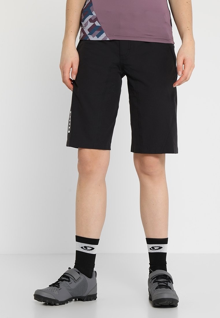 Mustat pyöräilyshortsit, joissa on slim fit -leikkaus, valmistettu kevyestä materiaalista. Yhdistetty harmaisiin pyöräilykengiin ja kuviollisiin sukkiin.