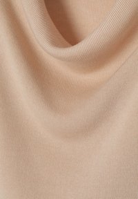 Svetle broskvové žebrované látky s jemnou texturou, která má volný a elegantní lodičkový výstřih a jemný lesk. Ideální pro vrstvení nebo pohodlné nošení.