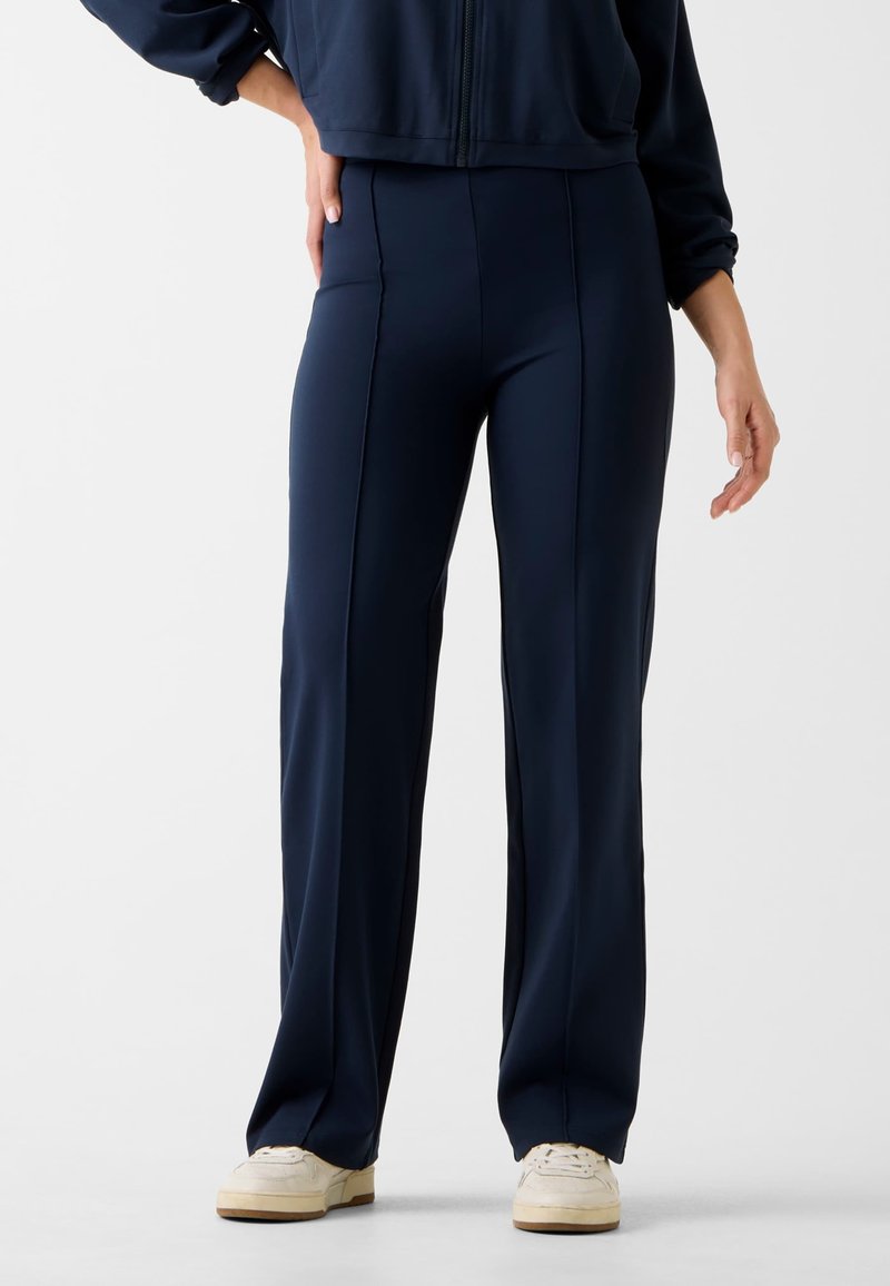 Marineblauwe sportbroek van rekbaar materiaal, met een hoge taille, rechte pijpen en subtiele naaddetails.