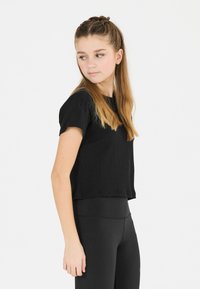 Schwarzes geripptes Crop-Top mit kurzen Ärmeln, kombiniert mit schwarzen Leggings. Der Stoff hat eine strukturierte Oberfläche, die für die Freizeit geeignet ist.
