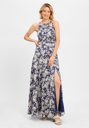 Robe maxi fluide à fleurs navy avec une fente haute et un design à encolure halter. Présente des motifs floraux crème et un tissu doux et léger.