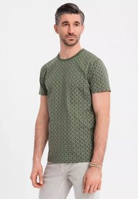 Zelené tričko s potiskem, kulatým výstřihem, krátkými rukávy a geometrickým vzorem. Měkká tkanina s jemnou strukturou.