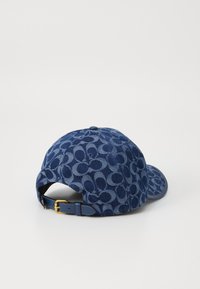 Denim kapa za baseball v temno modri barvi z vzorčastim dizajnom. Zapirala z zaponko in teksturirana tkanina na hrbtni strani.