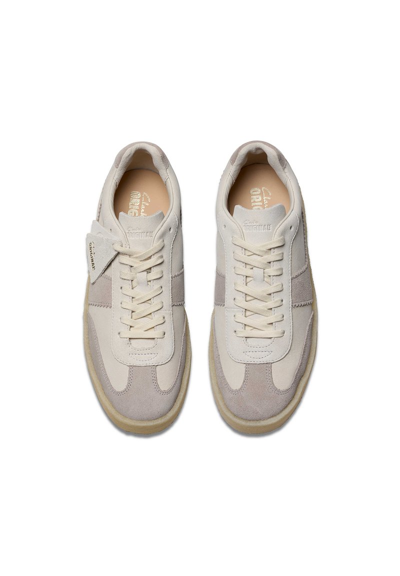 Sneaker beige e grigie con una tomaia in suede e pelle, punta rotonda, chiusura con lacci e suola in gomma con dettagli di branding discreti.