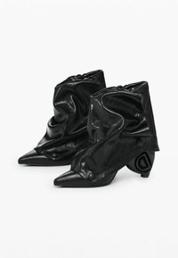 Botine negre până la gleznă din material lucios, cu un design lejer, vârf ascuțit și o formă unică a tocului, decorată cu detalii circulare.