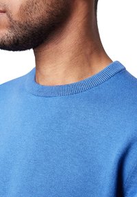 Blauer Rundhalsausschnitt-Pullover mit geripptem Kragen, der eine glatte Textur und ein eng anliegendes Design aufweist, geeignet für die Freizeit.