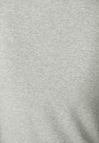 Tissu texturé gris clair avec un subtil motif chiné, offrant une finition douce et lisse adaptée à un style décontracté.