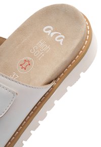 Close-up af en hvid læder slip-in sandal med beige polstret indersål mærket "ara High Soft" og størrelse 37, med hvide syninger.