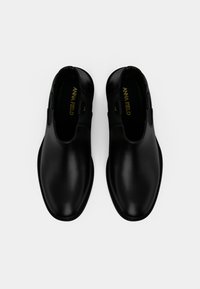 Μαύρες δερμάτινες παντόφλες με λεία επιφάνεια, στρογγυλή μύτη και μινιμαλιστικό σχέδιο. Διαθέτουν χρυσό λογότυπο στο εσωτερικό και διακριτικά στοιχεία.