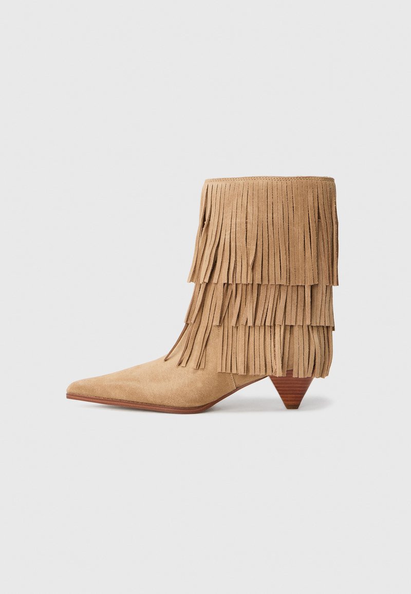 Tan-suede nilkkurit, joissa on kerroksellista fringedetailingia, kärjet ovat terävät ja kantapää on kartiomainen. Niissä on pehmeä pinta ja ainutlaatuinen silhouette.