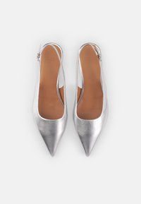 Zapatos slingback metálicos plateados con punta afilada, que presentan una textura suave y un diseño minimalista. Plantilla marrón con la marca visible.