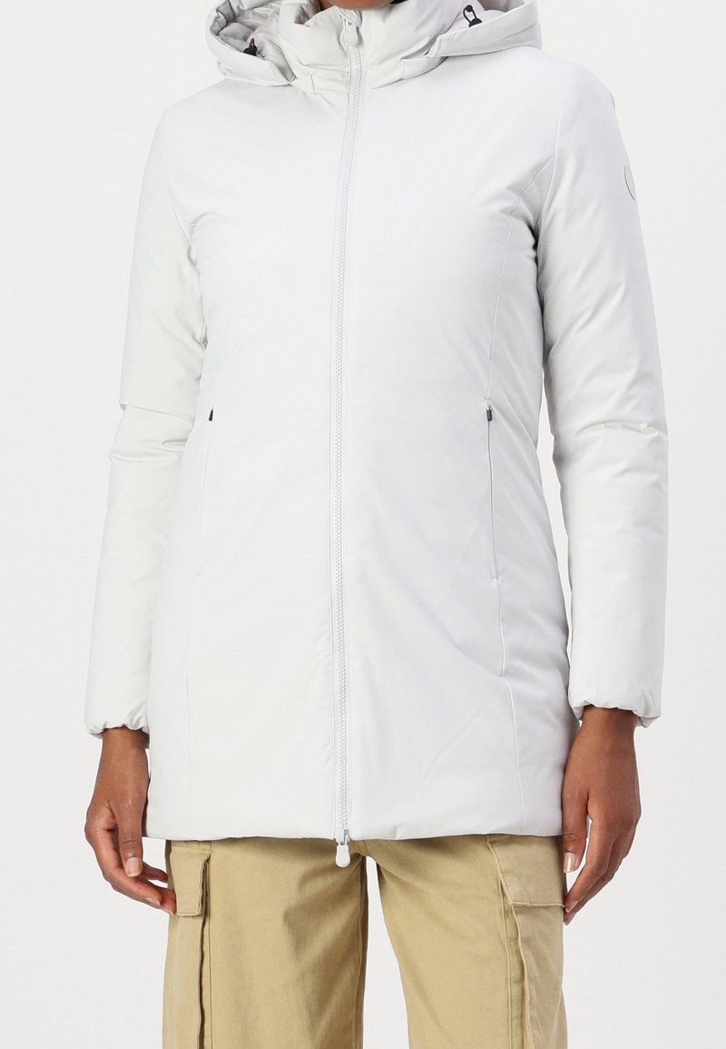 Blouson matelassé léger gris pâle avec capuche, fermeture éclair frontale, poches latérales et poignets élastiques. Texture lisse avec un léger éclat.