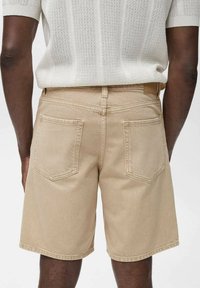 Khaki shorts made of cotton with a soft texture, featuring back pockets and a straight cut, paired with a light knit white top.