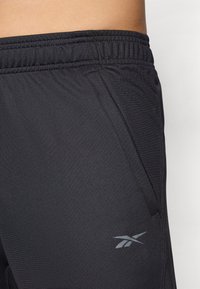 Melnas sporta bikses ar elastīgu jostu un sānu kabatām. Aizsargājošā apakšmalā ir neuzkrītoša pelēka logo. Izgatavotas no gludas, vieglas auduma.