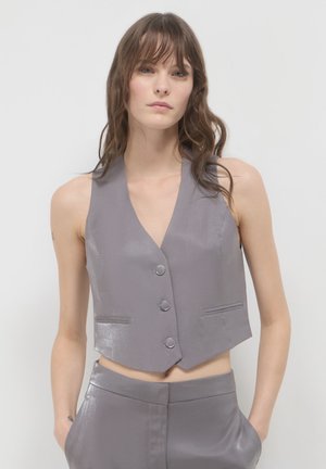 Gilet grigio senza maniche con scollatura a V, texture lucida, tre bottoni frontali e due tasche laterali, abbinato a pantaloni coordinati.
