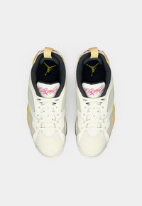 Ζεύγος λευκών και γκρίζων sneakers Jordan με μαύρη εσωτερική φόδρα, κίτρινες τακούνες, ροζ κείμενο "Flight" στις γλώσσες και κίτρινες λογότυπες μέσα.