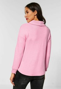 Maglione rosa con colletto ripiegato, maniche lunghe e vestibilità rilassata. Tessuto morbido, polsini a coste e orlo arrotondato.