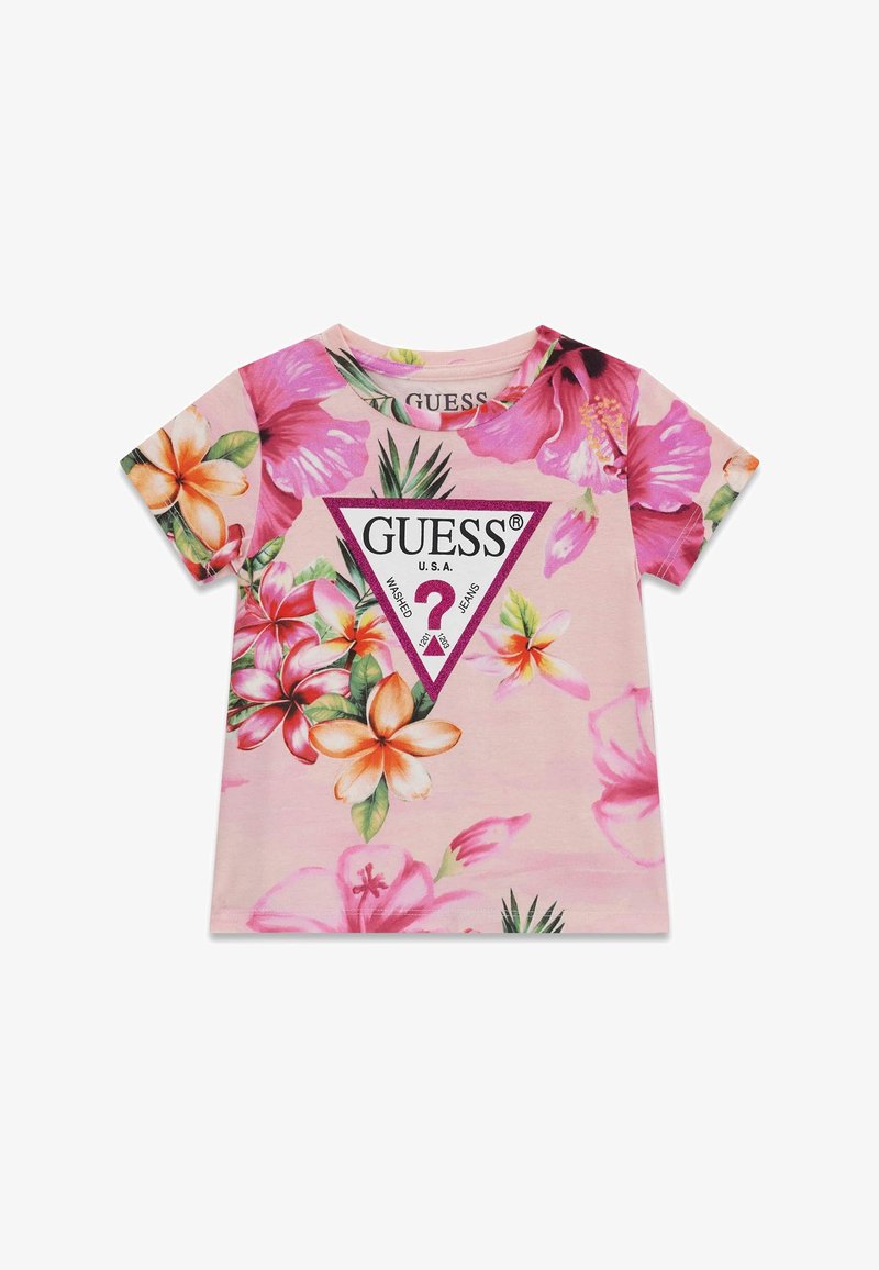 T-shirt rose à manches courtes avec de grandes fleurs tropicales colorées et un logo central GUESS violet en forme de triangle présentant un point d'interrogation.