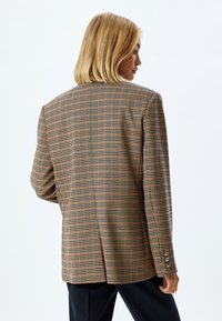 Braun kariertes Blazer mit grünen, roten und schwarzen Akzenten; verfügt über ein strukturiertes Design, Reverskragen, zwei Knöpfe und einen geschlitzten Rücken.