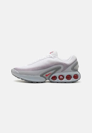 Chaussure de sport blanche et grise avec des coussins d'air rouges dans la semelle et un petit logo rouge sur le côté.