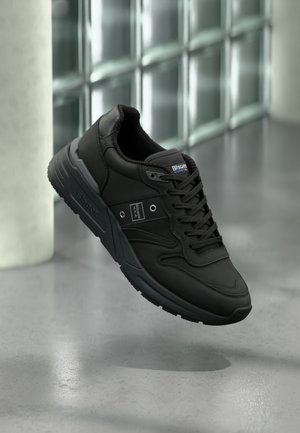 Black athletic shoe with a smooth leather upper, textured lining, lace-up design, and rubber sole featuring pronounced tread patterns.