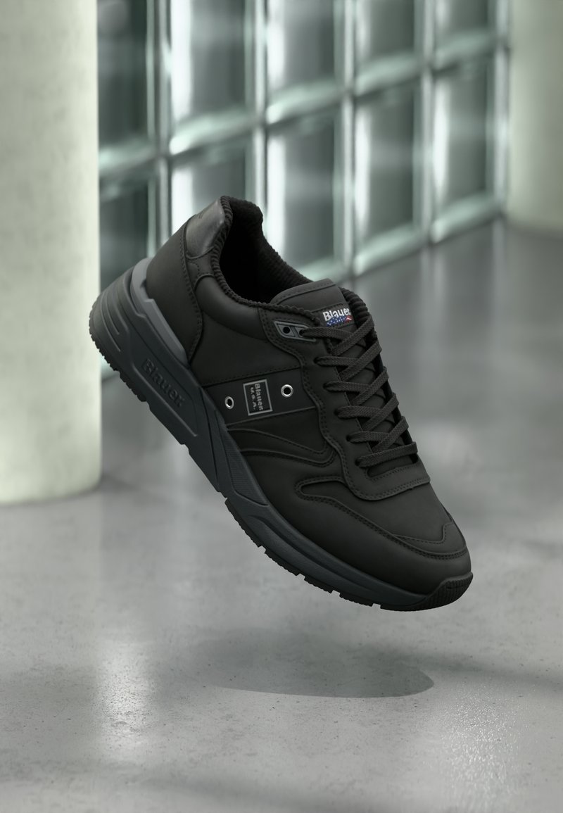 Schwarzer Sportschuh mit einer glatten Lederoberfläche, texturiertem Innenfutter, Schnürdesign und Gummisohle mit ausgeprägten Profilmustern.