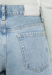 Jean en denim bleu clair avec une finition légèrement décolorée, dotés de poches arrière et d'une étiquette blanche gaufrée portant la mention "7 For All Mankind."