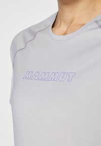 Lysegrå treningsskjorte med lilla "MAMMUT" logo, rund hals, korte ermer, og kontrastfargede sømdetaljer. Glatt tekstur.