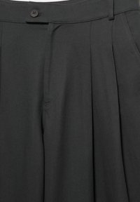 Pantalon plissé gris foncé avec une ceinture, une fermeture à bouton et des poches avant.