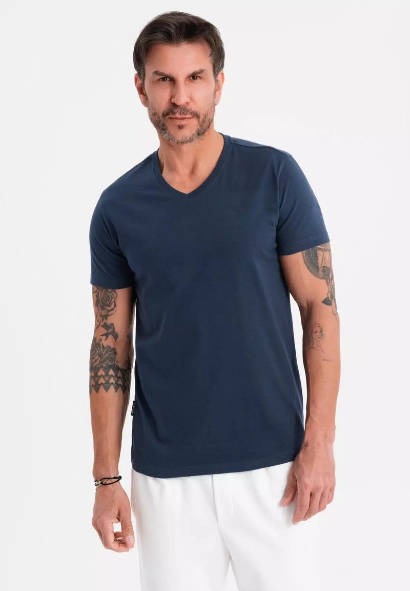 Námořnické bavlněné tričko s designem do V, krátkými rukávy a přiléhavým střihem. Výrazné tetování na pažích. Jednoduchá barva, hladká textura.