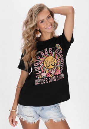 Zwarte katoenen T-shirt met kleurrijke vlinder- en bloemenafbeelding en de tekst "Blijf Groeien, Betere Dagen Komen Eraan". Korte mouwen en een relaxte pasvorm.