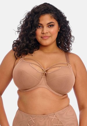 Bra in a light tan color with soft fabric, underwire support, cut-out design with a heart accent, and adjustable straps.